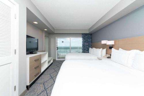 a hotel room with two beds and a television at DoubleTree Suites by Hilton Melbourne Beach Oceanfront in Melbourne