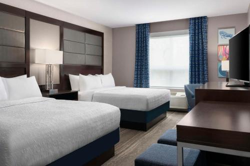 a hotel room with two beds and a desk at Hampton Inn & Suites-Worcester, MA in Worcester