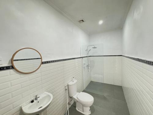 a white bathroom with a toilet and a sink at Palma House Kelingking in Nusa Penida