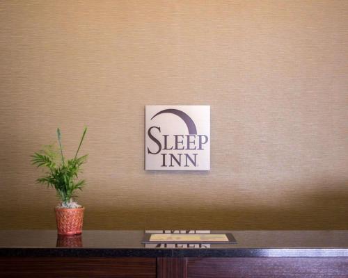 a sign on a wall with a potted plant on a desk at Sleep Inn Wilson near I-95 in Wilson