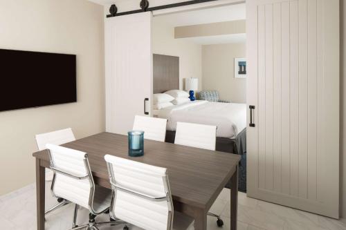 a dining room with a table and chairs and a bed at Hotel Renovo Des Moines Urbandale,Tapestry Collection Hilton in Urbandale