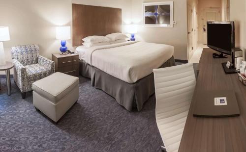 a hotel room with a large bed and a television at Hotel Renovo Des Moines Urbandale,Tapestry Collection Hilton in Urbandale