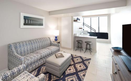 a living room with a couch and a kitchen at Hotel Renovo Des Moines Urbandale,Tapestry Collection Hilton in Urbandale