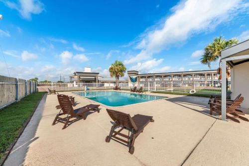 a swimming pool with rocking chairs next to a building at Quality Inn & Suites Port Lavaca near Lighthouse Beach in Port Lavaca