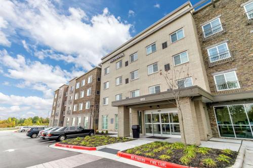 a large brick building with cars parked in a parking lot at WaterWalk Extended Stay Raleigh Durham Research Triangle in Durham