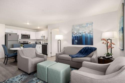 a living room with a couch and chairs and a kitchen at WaterWalk Extended Stay by Wyndham Minneapolis - Plymouth in Plymouth