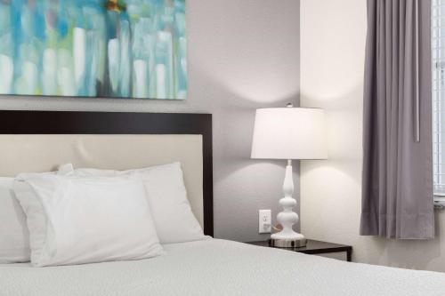 a bedroom with a white bed and a lamp at WaterWalk Extended Stay by Wyndham Minneapolis - Plymouth in Plymouth
