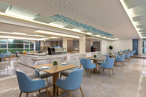 a restaurant with tables and chairs and a counter at Wyndham Garden Rizhao Donggang Resort in Rizhao