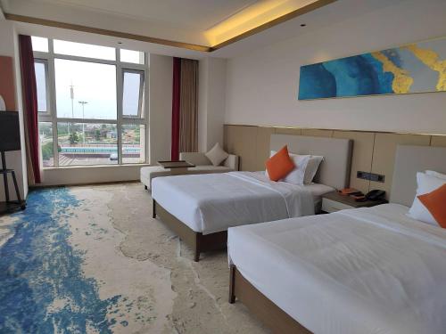 a hotel room with two beds and a couch at Wyndham Garden Rizhao Donggang Resort in Rizhao