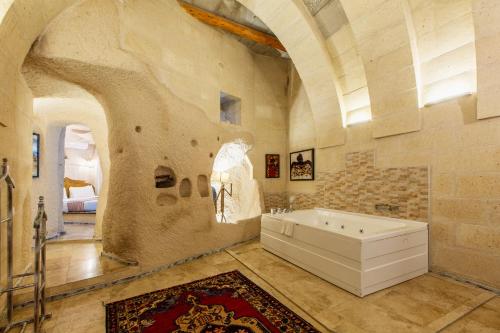 a bathroom with a bath tub in a stone wall at Karlık Cave Suite Cappadocia in Uchisar