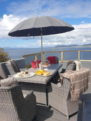 a table and chairs with an umbrella on a deck at Tom Jacks, coastal views and beach walks Connemara in Galway