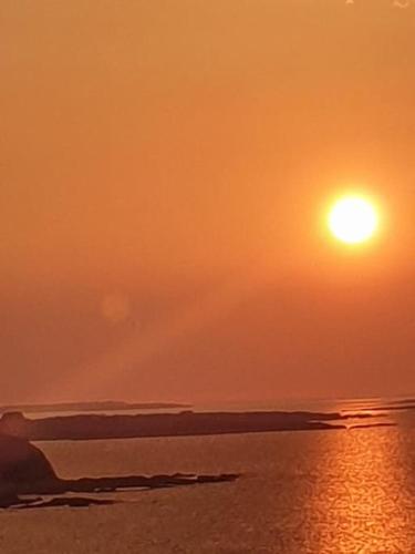 a sunset over the ocean with the sun in the sky at Tom Jacks, coastal views and beach walks Connemara in Galway
