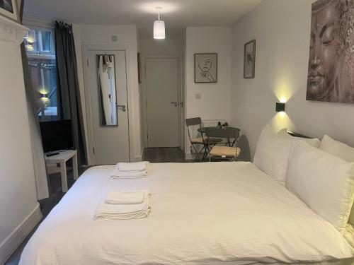 Un dormitorio con una gran cama blanca con dos toallas encima. en Amazing studios 2 - East London, en Londres