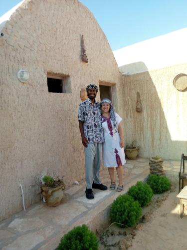 a man and a woman standing in front of a building at Dar alibaba in Douz