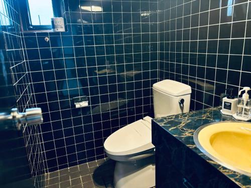 a blue tiled bathroom with a toilet and a sink at SAMURISE No.4 in Fujikawaguchiko