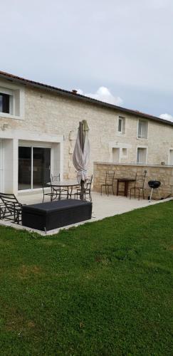 un bâtiment avec bancs et table avec un parasol dans l'établissement Gite a la campagne, à Bougneau
