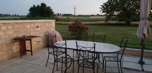 une table et des chaises assises sur une terrasse dans l'établissement Gite a la campagne, à Bougneau