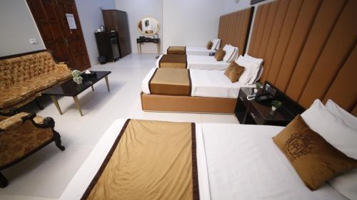 a hotel room with four beds and a television at Four Squares by WI Hotel in Karachi