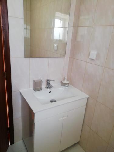 a bathroom with a white sink and a mirror at Casa do Forno in Lajes das Flores