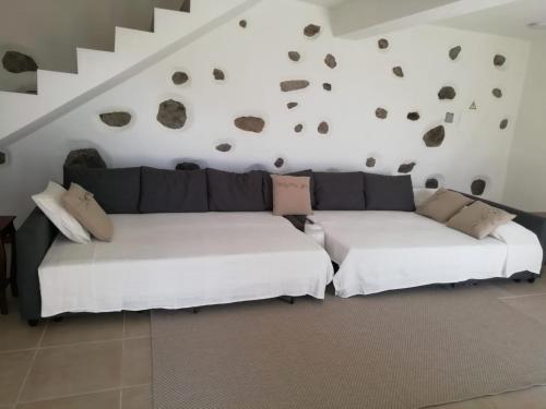 two white couches in a living room with rocks on the wall at Casa do Forno in Lajes das Flores