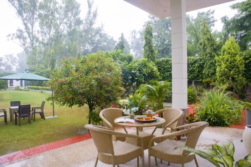 a patio with a table and chairs and a garden at Alaya Stays 3 BHK Pet friendly with Pvt Pool - Daffodil in New Delhi