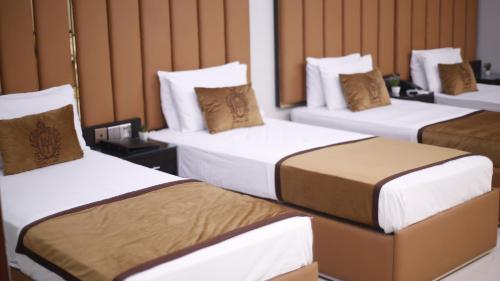 a group of three beds in a room at Four Squares by WI Hotel in Karachi