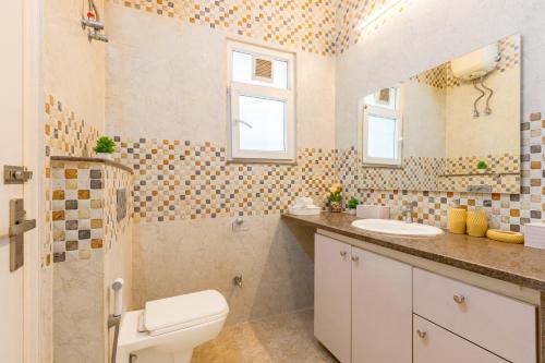 a bathroom with a toilet and a sink at Alaya Stays 3 BHK Pet friendly with Pvt Pool - Daffodil in New Delhi