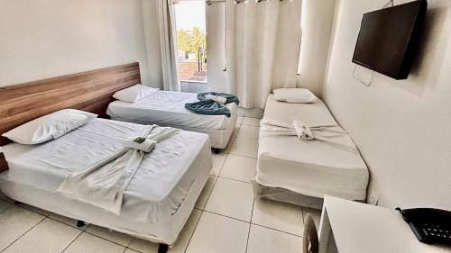 two beds in a room with a window at POUSADA MEDITERRÂNEO in Lagarto
