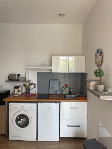 une cuisine avec une machine à laver et un lave-linge dans l'établissement Studio lumineux au calme en centre ville, face aux thermes, à Salies-de-Béarn