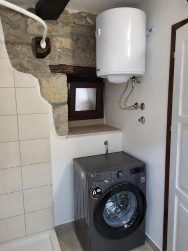 a washing machine in a bathroom with a stone wall at Apartman studio Baladur in Roč