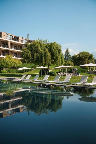 a pool of water with tables and umbrellas next to a building at Hotel Seehof Nature Retreat in Naz-Sciaves