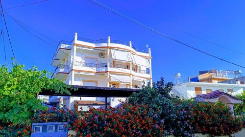 a tall white building with flowers in front of it at Nitro Inn Orikum - SEA and GARDEN in Orikum