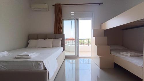 a white bedroom with two beds and a balcony at Nitro Inn Orikum - SEA and GARDEN in Orikum