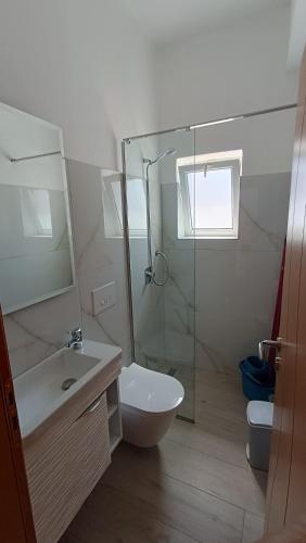 a bathroom with a toilet and a sink and a shower at Nitro Inn Orikum - SEA and GARDEN in Orikum