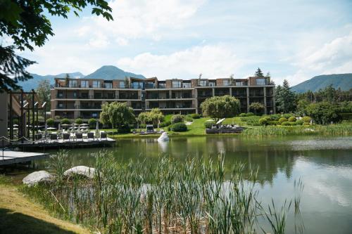 a hotel with a lake in front of it at Hotel Seehof Nature Retreat in Naz-Sciaves