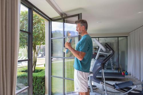 a man on a treadmill holding a glass of wine at Hotel Seehof Nature Retreat in Naz-Sciaves