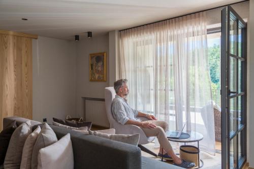 a man sitting in a chair in a living room at Hotel Seehof Nature Retreat in Naz-Sciaves