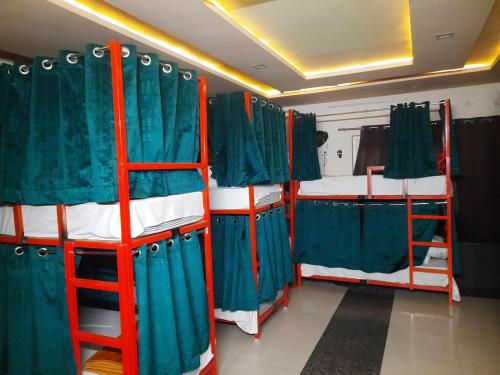 a room with three bunk beds with green curtains at HOTEL SATYA in Dehradun