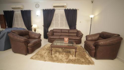 a living room with two leather chairs and a coffee table at Four Squares by WI Hotel in Karachi