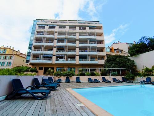 un hôtel avec une piscine, des chaises et un bâtiment dans l'établissement Cocon d'Azur, à Cannes