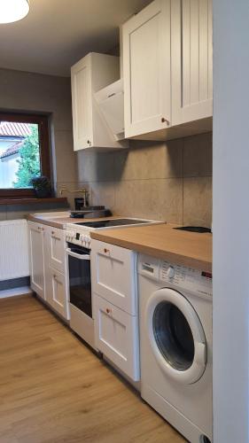 トルンにあるKawalerka 40 m 2 osoby ulica Porzeczkowa Torunのキッチン(白いキャビネット、洗濯機、乾燥機付)