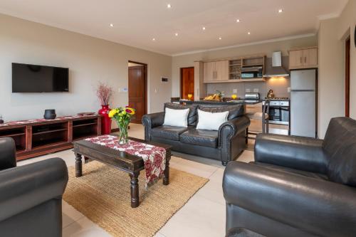 a living room with leather furniture and a kitchen at Alkantmooi Private Nature Reserve - Keurkloof & Keurbos 93 in Plettenberg Bay