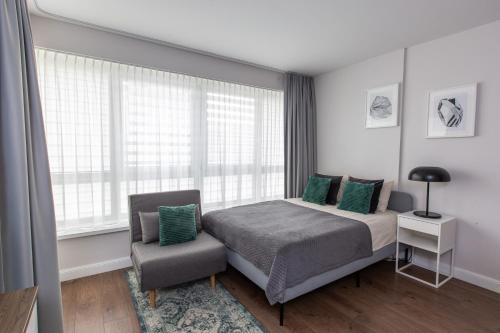 une chambre avec un lit, une chaise et une fenêtre dans l'établissement Studio Ligita near Egle, à Druskininkai