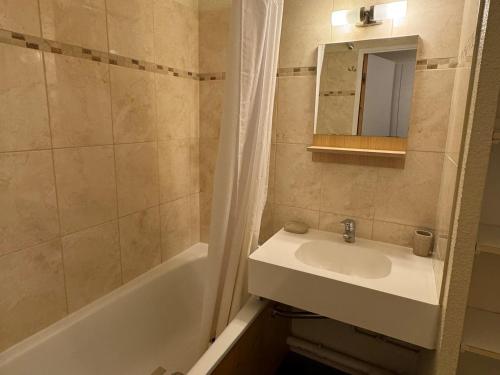 une salle de bain avec un lavabo, une baignoire et un miroir dans l'établissement Appartement confortable au pied des pistes avec balcon et parking - FR-1-181-2055, à La Plagne Tarentaise