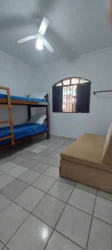 a bedroom with a bed and a ceiling fan at Sua casa longe de casa in Mongaguá