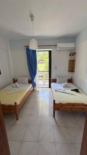 two beds in a room with a door to a patio at Villa ΝOSTALGΙΑ in Kókkinon Nerón