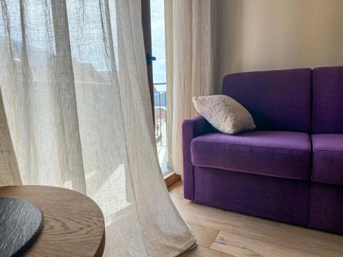 a purple couch in a living room with a window at Vivi Suites & Spa - Boutique Guest House Molveno in Molveno