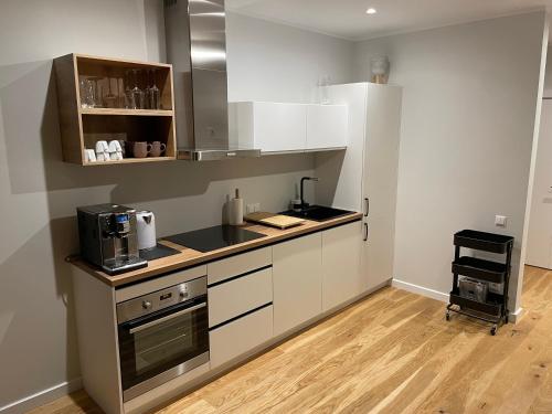 a kitchen with white cabinets and a stove top oven at Suite am Meer / Seaside suite in Ķesterciems