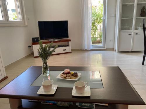 a coffee table with a plate of food and two cups at Oleander in Podstrana