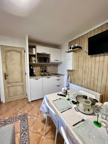 une cuisine avec une table et des placards blancs dans l'établissement Appartement Perce-Neige, à Thollon-les-Mémises
